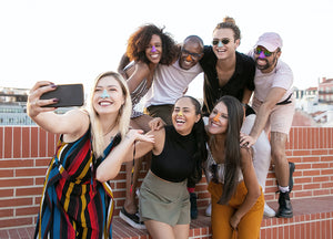 Group of friends protecting their faces with Nöz’s Eco friendly & colorful spf sunscreen at the beach. 